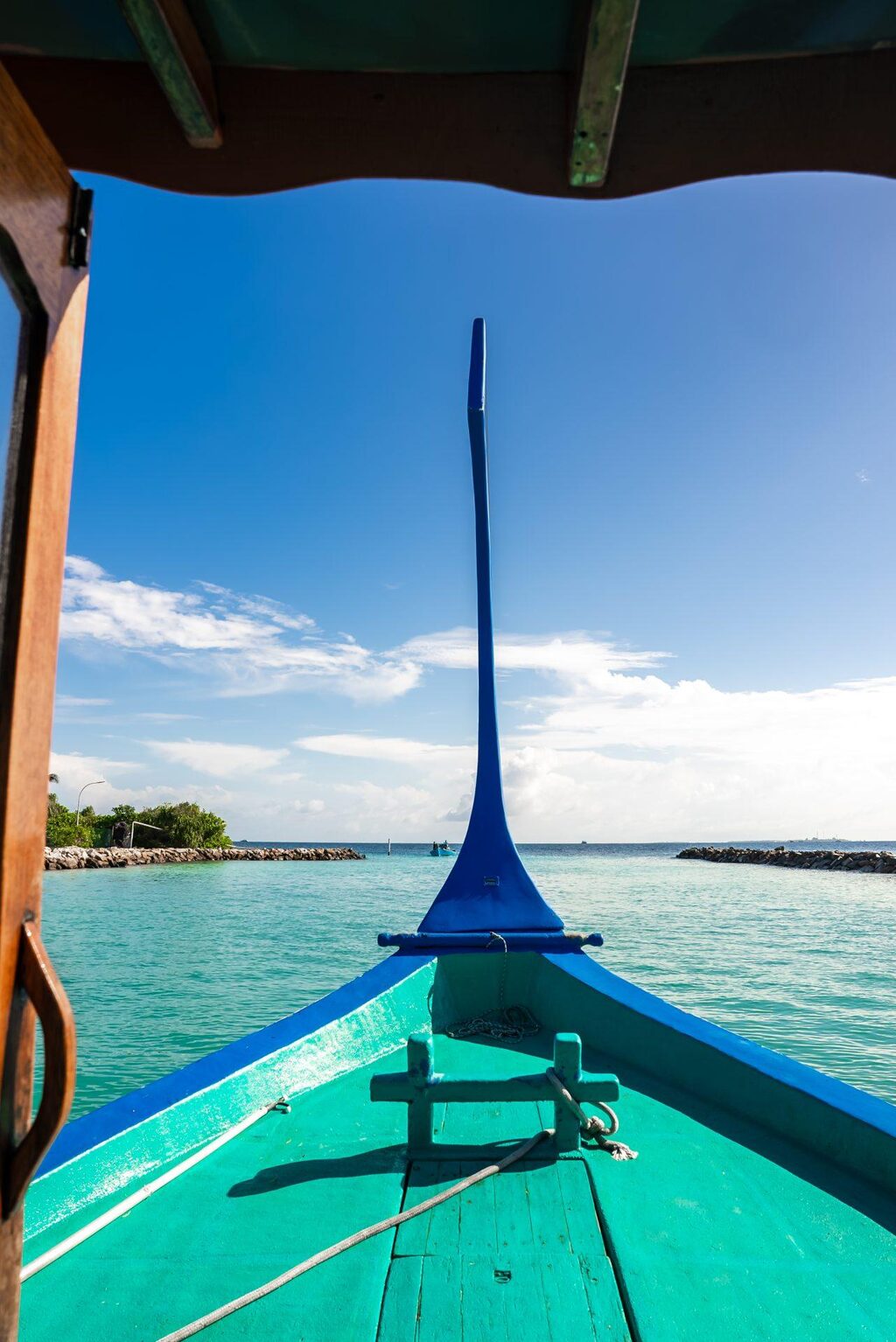 The bow of a traditional Maldivian dhoni crossing turquoise water