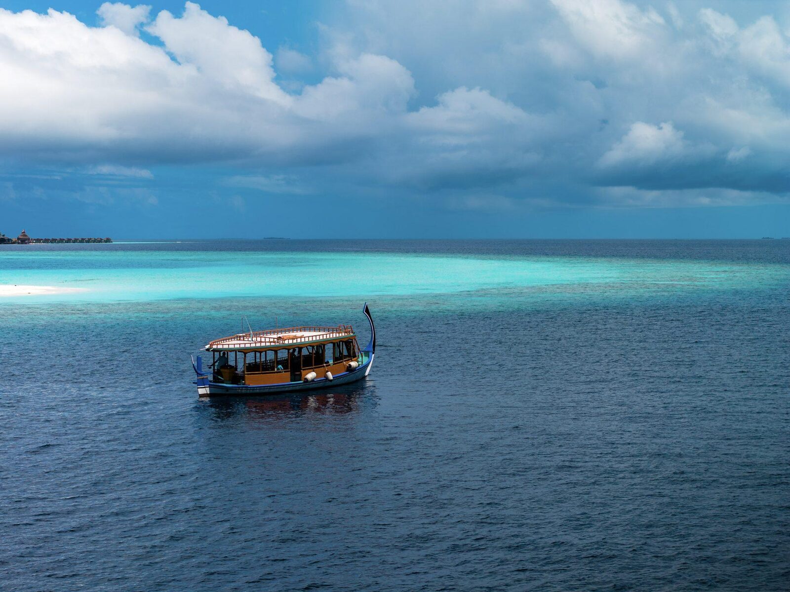 A dhoni on the turquoise shallows near the reef edge at Dhigurah